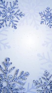 Mavi arka planda pırlanta parıltısıyla kaplı kristal kar taneleri. Parlak ışık efektli bir Noel süsü. Döngü. Dikey video.