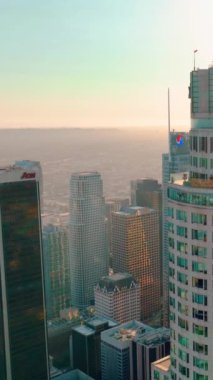 Los Angeles, CA, ABD - 15 Eylül 2024: Los Angeles şehir merkezinin hava görüntüsü. Kamerayı uzun gökdelenler boyunca indiriyorum. AON ofis binası. Dikey video.