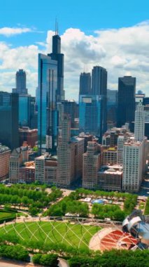 Chicago şehir merkezindeki yeşil parkların ve eğlence alanlarının havadan görüntüsü. Bulutlu mavi gökyüzüne karşı ünlü gökdelenler. Dikey video.