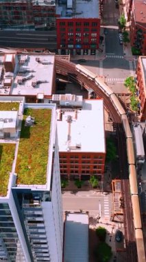 Chicago, Illinois, ABD - 01 Haziran 2024: Yükseltilmiş tren rayları Chicago 'daki döngü hattındaki bina arasındaki demiryolu rayları üzerinde çalışıyor. Hava görüntüsü. Dikey video.