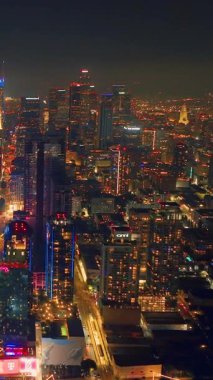 Los Angeles, CA, ABD - 15 Eylül 2024: Los Angeles şehir merkezinin gece hava görüntüleri. Ünlü gökdelenlerin finans bölgesi manzarası. Dikey video.