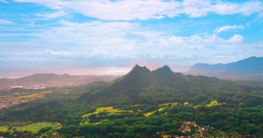 Olomana Dağı 'ndan Oahu adasının resimli yeşil manzarasının panoramik görüntüsü. Pasifik sahilinde bulutlu mavi gökyüzü.