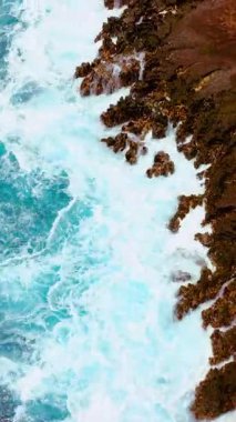 Büyük okyanus dalgalarının havadan görünüşü Hawaii adasının kayalık kayalıklarına çarpıyor. Dikey video.