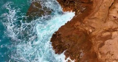 Deniz köpüğüyle kıyıda büyük dalgalar kopuyor. Oahu adasının Pasifik kıyısındaki kayalık volkanik kayaların yukarıdan aşağı görüntüsü..