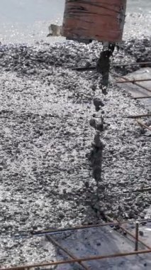 Beton çelik destek çubuklarının üzerine dökülüyor. Beton karışımını yüzeye dökmeye yakın çekim. Dikey video.