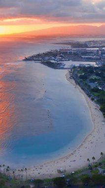 Okyanus ufkunda gün batımı. Mavi sular ve Ala Moana 'daki kumlu plajlar. Honolulu 'nun havadan görünüşü. Dikey video.