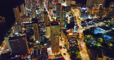 Geceleri Honolulu şehir merkezinin hava manzarası. Parlak ışıklı sokaklar ve ışıklı oteller. Waikiki Rıhtımı Alacakaranlıkta.