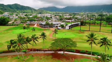 Honolulu 'daki yeşil golf sahalarına karşı Oahu' daki volkanik dağlar. Spor kulübündeki palmiye ağaçlarının ve bitki örtüsünün havadan görünüşü.