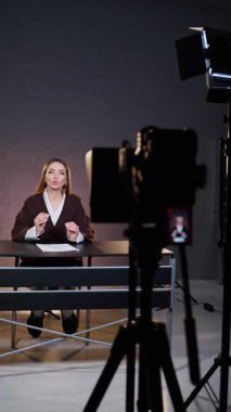 Masadaki kimonolu genç kız teleprompter ile kameraya konuşuyor. Ekipmanlı profesyonel video stüdyosu. Sosyal ağlar için video kaydı. Dikey video.