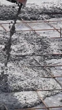Ezilmiş taşla sıvı beton karışımı demir destekli ızgarayla bir borudan zemine dökülür. Beton levhanın inşaatı. Dikey video.