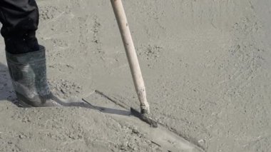 Islak beton yüzeyini inşaat alanındaki özel bir aletle düzleştirmek. Bir inşaatçının el işi. Yakın plan..