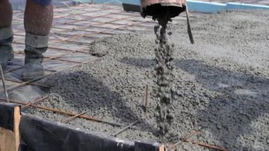 Bir evin temelini atmak için boruyla beton besleyen bir makine. İnşaat çalışmalarına yakın çekim. Yerdeki demir şebekesi takviye ediliyor..