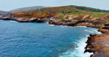 Okyanus kıyısındaki doğal volkanik kayalar. Dalgaların dalgalandığı mavi sular Hawaii 'nin Oahu adasının kıyısındaki kayalara çarpıyor. Hava görünümü.