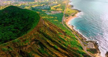 Oahu adasındaki Koko krater volkanı. Pasifik kıyısında evleri olan dağ yamaçlarının ve yeşil vadinin havadan görünen manzarası..