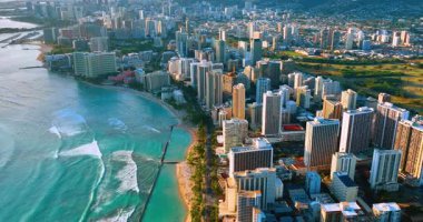 Waikiki sahilinin havadan görünüşü lüks tatil köyleri, palmiye ağaçları, Honolulu, Hawaii, Birleşik Devletler. Gün batımında şehrin manzarası. Rıhtımda lüks oteller var..