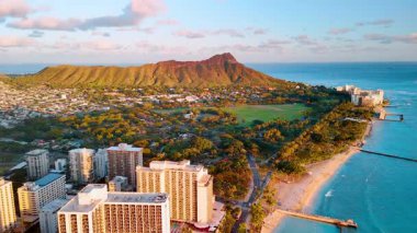 Elmas Kafa volkanının akşam güneşindeki görüntüsü. Okyanus kıyısında mavi suyu olan oteller ve konut binaları.