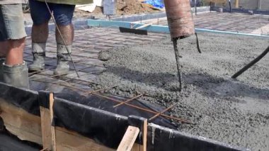 İnşaat alanındaki beton döküm inşaat alanındaki çelik parmaklıkların güçlendirilmesi üzerine dökülüyor. İşçiler betonu titretiyor..