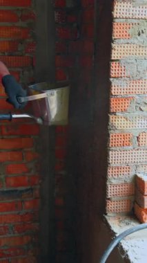 Tuğla duvarlara kum çimentoyla ıslatılmış alçı püskürtme uygulaması. İnşaat alanında dekoratif işleri bitirmek. Dikey video.