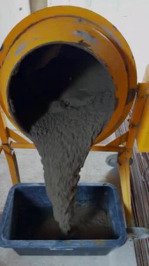 Beton mikserden dikdörtgen plastik bir kaba dökülüyor. Karıştırıcı sarı bir çerçeveye monte edilmiş ve aşağı doğru eğilmiş. Dikey video.