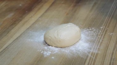 Ekmek somunu şeklinde hamurun üzerine un düşüyor. Fırındaki ahşap mutfak masasına un düştü. Ekmek yapma süreci. Yavaş çekim.