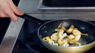 Şef tavada mantar pişiriyor. Yakın çekim. Lokantadaki sobanın üstünde demir tavada kızartıcı mantarlar..