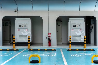 Elektrik şarj istasyonu, şehrin otoparkında mavi ve beyaz renklerle dekore edilmiş boş bir şarj aleti.