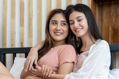 Asyalı genç ve güzel bir kadın ve kız arkadaşı, yatak odasında mutlulukla dudaklarına sarılıp öpüşüyorlar. Kadın aşığın romantik zamanı, LGBTQ aşk özgürlüğü kavramı, kopyalama boşluğu.