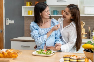 Asyalı genç ve güzel bir kadın ve kız arkadaşı mutfakta mutlulukla yemek yiyorlar. Kadın aşığın romantik zamanı, LGBTQ aşk özgürlüğü kavramı, kopyalama alanı.