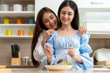 Genç Asyalı kadın ve kız arkadaşı, mutfakta aşkla kucaklaşıp öpüşüyorlar. Kadın aşığın romantik anı, aşk özgürlüğü konsepti, fotokopi makinesi.