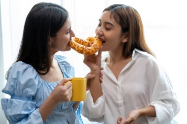 Mutlu Asyalı genç ve güzel kadın ve kız arkadaşı ellerinde kahve fincanları ve mutfakta sohbet ediyorlar kadın aşığın romantik zamanı, LGBTQ aşk özgürlüğü konsepti, kopyalama boşluğu.