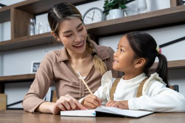 Güzel bir anne, güzel kızına evde ödev yapmayı öğretiyor. Konuşuyorlar ve gülüyorlar. Birlikte mutlu mesut.