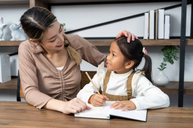 Güzel bir anne, güzel kızına evde ödev yapmayı öğretiyor. Konuşuyorlar ve gülüyorlar. Birlikte mutlu mesut.