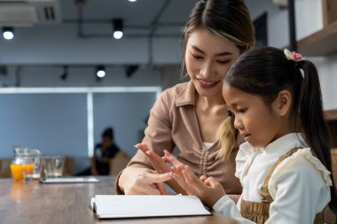 Güzel bir anne, güzel kızına evde ödev yapmayı öğretiyor. Konuşuyorlar ve gülüyorlar. Birlikte mutlu mesut.