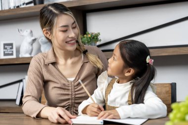 Güzel bir anne, güzel kızına evde ödev yapmayı öğretiyor. Konuşuyorlar ve gülüyorlar. Birlikte mutlu mesut.