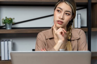 Düşünceli Asyalı genç kadın evde çalışırken laptop monitörüne bakıyor, boşluğu kopyala