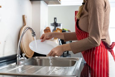 Yaklaş, şef şapkası ve önlüğü takmış güzel kadın evde bulaşık yıkıyor, boşluğu kopyalıyor.