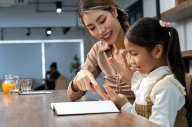 Güzel bir anne, güzel kızına evde ödev yapmayı öğretiyor. Konuşuyorlar ve gülüyorlar. Birlikte mutlu mesut.