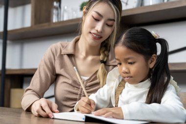 Güzel bir anne, güzel kızına evde ödev yapmayı öğretiyor. Konuşuyorlar ve gülüyorlar. Birlikte mutlu mesut.