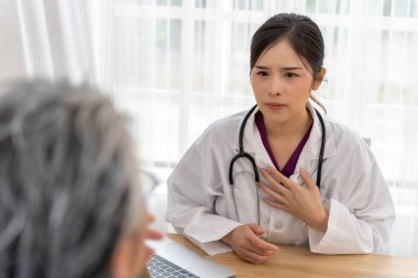 Seçici odaklanma, Asyalı genç doktor semptomları soruyor ve yaşlı kadının sağlık hizmetlerine tavsiye veriyor, masadaki dizüstü bilgisayar, kopyalama alanı