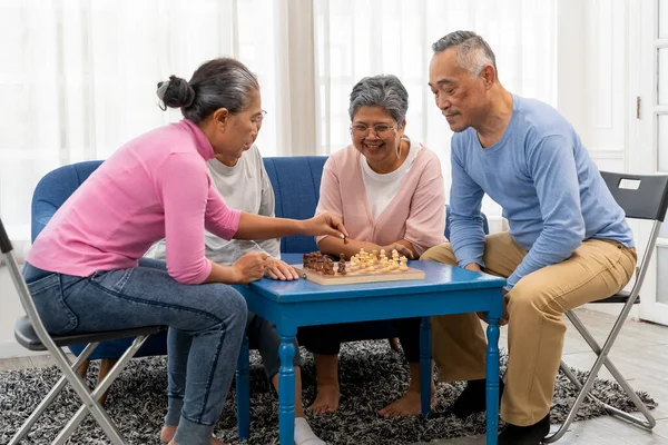 stock image Group of asian senior people sitting on sofa and chair and enjoy to playing chess at nursing home, Happy relax time together with friends, talk and smile with fun together