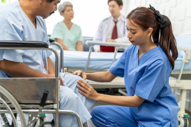 Genç kadın doktor, yaşlı hastanın dizine dokunuyor, kadın cerrah, hastanedeki ameliyattan sonra dizlerinin durumunu kontrol ediyor.