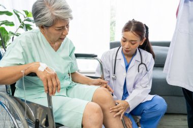 Genç kadın doktor, yaşlı hastanın dizine dokunuyor, kadın cerrah, hastanedeki ameliyattan sonra dizlerinin durumunu kontrol ediyor.