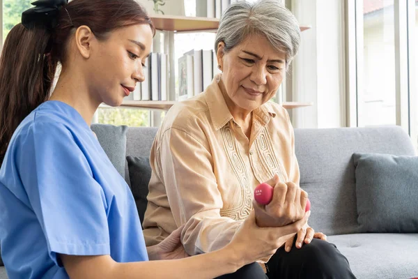 Asyalı genç fizyoterapist kadın hasta için evde halterli egzersiz, sonrasında bakım ve fizyoterapi konsepti