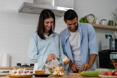 Çekici, genç, güzel bir eş ve yakışıklı bir koca modern mutfakta yemek pişirirken mutlu mesut vakit geçiriyorlar.