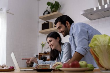 Çekici, genç, güzel bir eş ve yakışıklı koca, modern mutfakta yemek pişirirken birlikte vakit geçirmekten mutlular..