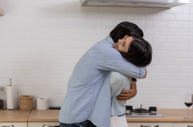 Mutfakta kucaklaşan romantik sevgili, evlenme teklif eden genç yakışıklı adam, kız arkadaşına sürpriz yapmak için bir yüzük ver, ona evde evlenme teklif et, birlikte evlensinler.