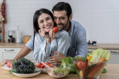 Çekici genç çift mutfakta birlikte yemek pişiriyor, romantik sevgili ve sevgili samimi bir anı paylaşıyor, ilişkilerinin tadını çıkarıyor ve birlikte kaygısız kalıyorlar, boşluğu kopyalıyorlar.