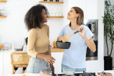 İki Kadın ev mutfağında yemek pişiriyor. Genç ve güzel bir kadın mutfakta ayakta duruyor ve elinde sağlıklı yiyeceklerle yemek hazırlıyor. Sağlıklı yaşam tarzı. Evde Pişirme. 