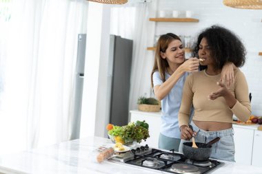 İki Kadın ev mutfağında yemek pişiriyor. Genç ve güzel bir kadın mutfakta ayakta duruyor ve elinde sağlıklı yiyeceklerle yemek hazırlıyor. Sağlıklı yaşam tarzı. Evde Pişirme. 