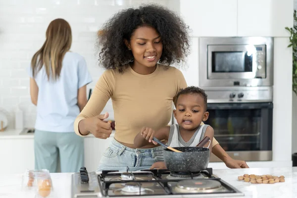 Young women teach little children to cook in a modern kitchen. Young pretty woman and child standing preparing lunch in kitchen she making Healthy Food. Healthy Lifestyle. Cooking At Home.